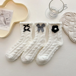 Trois paires de chaussettes en polaire corail blanche avec nœuds et fleurs sur plateau