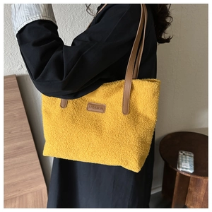 Detail view of yellow plush tote bag featuring soft faux fur texture and brown leather straps
