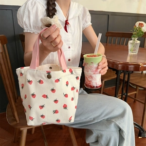 Vue détaillée du sac en velours côtelé fraise avec poignées roses et boucle en métal