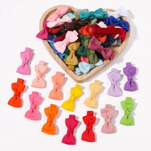 Detail of colorful 2-inch grosgrain ribbon bow clips in a heart-shaped wooden tray