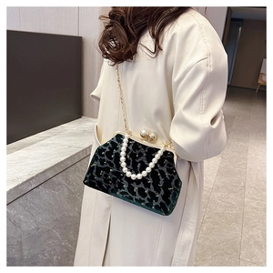 Detail view of dark green velvet shell bag with black patterns and pearl handle strap