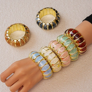 Close-up of colorful acrylic resin bangles with gold alloy edges and elastic band