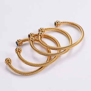 Détail de bracelets câbles dorés avec des pierres précieuses colorées aux extrémités
