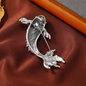 Silver koi fish brooch back view showing high-quality safety pin on brown silk fabric