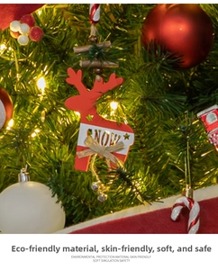 Wooden reindeer ornament with SNOW design and bell hanging on a Christmas tree branch