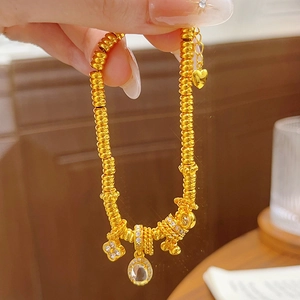 Detailed macro view of 24k gold clover charm bracelet with sparkling crystals