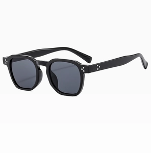 Close-up of retro oval sunglasses with black frames and decorative silver dot accents