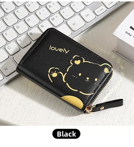 Detail of black PU leather card wallet with cute bear print and gold zipper on a desk