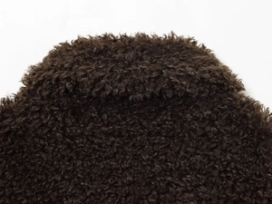 Close-up detail of dark brown fleece jacket fabric with thick grainy texture