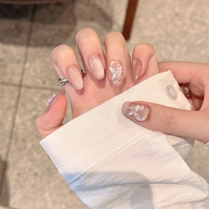 Close-up of handmade press-on nails with ice crystal butterfly and cat-eye blush
