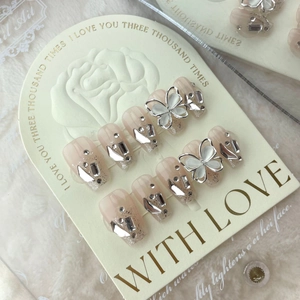 Handmade cat-eye press-on nails in nude pink with 3D butterfly charms and rhinestones