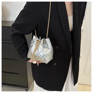 Detail of silver quilted bucket bag with golden chain strap and pearl accents