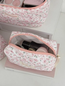 Detail view of pink floral corduroy cosmetic bag set with zipper and brand label