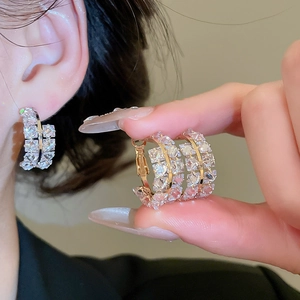 Vue macro de boucles d'oreilles créoles dorées avec zircons étincelants sur un modèle