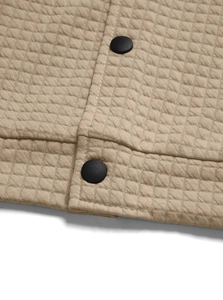 Detail of khaki quilted fabric with diamond pattern and two black matte buttons on collar