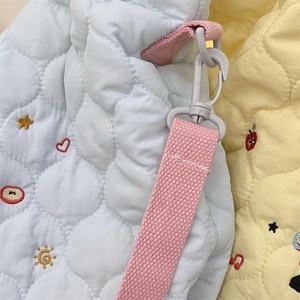 Détail macro de tissu matelassé avec broderie colorée et bandoulière tissée rose