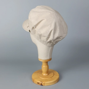 Détail de la casquette gavroche beige en coton et lin montrant la texture et le bouton latéral
