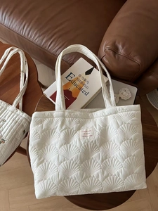 Close-up of white quilted tote bag featuring shell stitch pattern and fabric label
