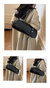 Detail of glossy black baguette shoulder bag with wide strap and silver buckle accents
