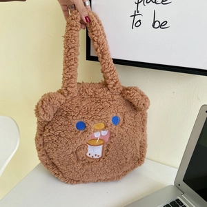 Detail of a brown fuzzy plush bear handbag with cute embroidery and sturdy top handles