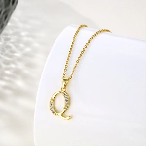 Macro view of gold 925 silver letter Q pendant with zircon stones on a cross chain