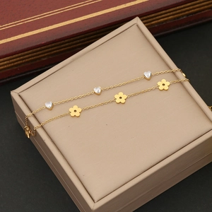 Detail of golden double-layer bracelet with heart zircon and flower pendants on a jewelry box