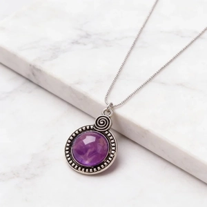 Vue détaillée du pendentif vintage en résine violette avec gravures métalliques