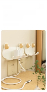 Macro detail of wall-mounted plug holder with wood knob storing phone charger and cable