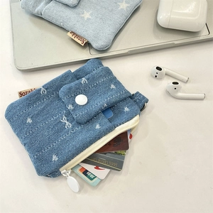 Close-up of blue denim card holder featuring white floral patterns and zipper detail