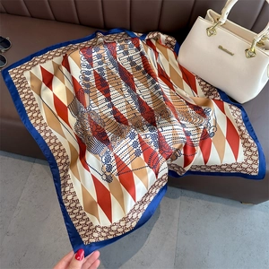 Blue-edged diamond pattern silk scarf styled on a leather sofa with fashion accessories