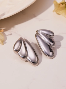 Macro shot of silver angel wing stud earrings with polished finish on marble surface