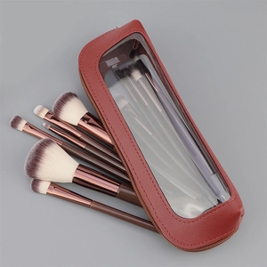 Detail van 13 koffiekleurige make-up borstels met roségouden ringen in een lederen etui