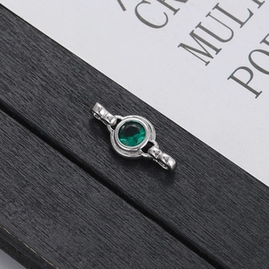 Detail of silver connector clasp featuring a round green zircon stone on wood