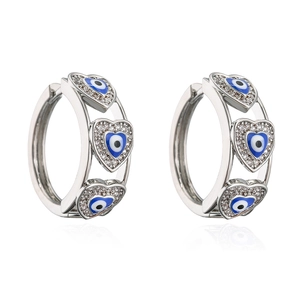 Macro detail of heart-shaped hoop earrings with blue eye charms and cubic zirconia