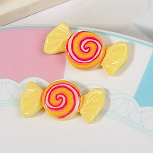 Macro detail of yellow resin candy charms with vibrant orange and red swirl patterns