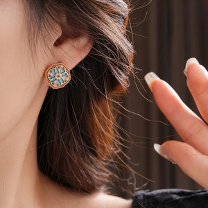 Macro detail of hexagonal vintage earrings with floral enamel and gold plating on model
