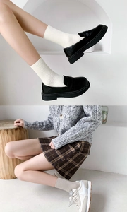 Close-up of ribbed crew socks paired with black platform loafers and casual beige sneakers