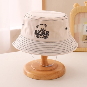 Detail of beige canvas kids sun hat with bear embroidery and white elastic chin strap