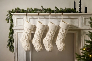 Set of 4 cream white knit Christmas stockings hanging on a white fireplace mantel