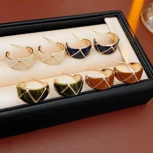 Detail view of four vintage enamel C-shaped earrings in cream, navy, green and brown