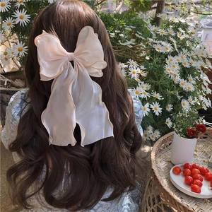 Elegant large organza bow hair clip with long ribbons on wavy brown hair