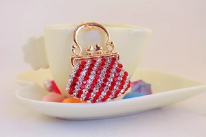 Close-up of golden handbag charm with red and white rhinestones on heart tray