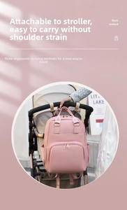 Pink multipurpose diaper bag shown hanging on a stroller with gold zipper detail
