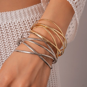 Detailed view of layered geometric crossover bangles in gold and silver finish