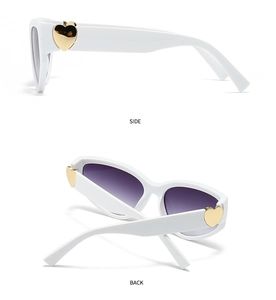 Detail view of white sunglasses featuring large gold heart metal decor on side and back