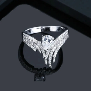 Détail macro d'une bague ailée en argent avec zircone poire sur surface miroir noire