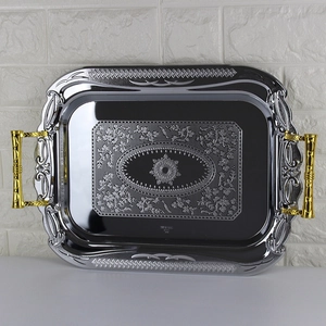Macro shot of rectangular stainless steel tray featuring gold handles and floral engravings