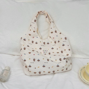 Detail of cartoon bread dog pattern on cream pleated canvas tote with brand patch