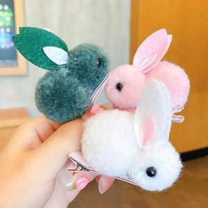 Detailed view of plush rabbit hair clips in white, pink, and green with fabric wrapped metal clips