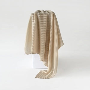 Detail of champagne gold pleated scarf showing silk-like texture and fine plissé fabric